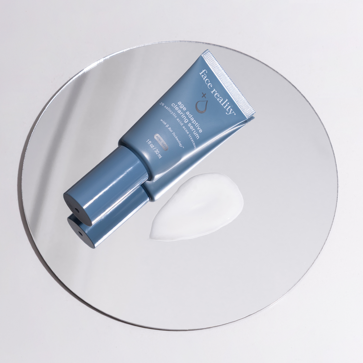 Face Reality Age Adaptive Clearing Serum tube on a glass disc showing the serum texture